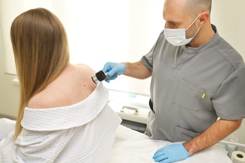 dermatologist examines neoplasms on the patient's skin using a special dermatoscope device. prevention of melanoma.